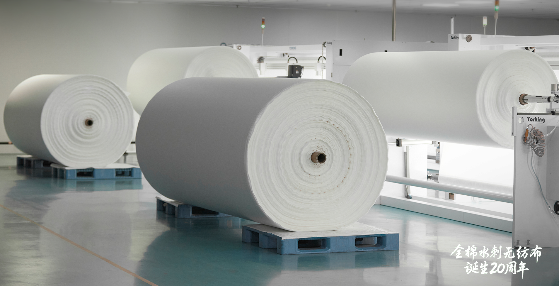Large rolls of all-cotton spunlace fabric staged in the finishing area